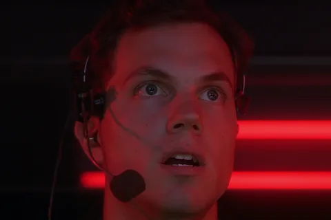 Garber wearing a headset and staring up at the monitors under red light in the OWLF command trailer in Predator 2