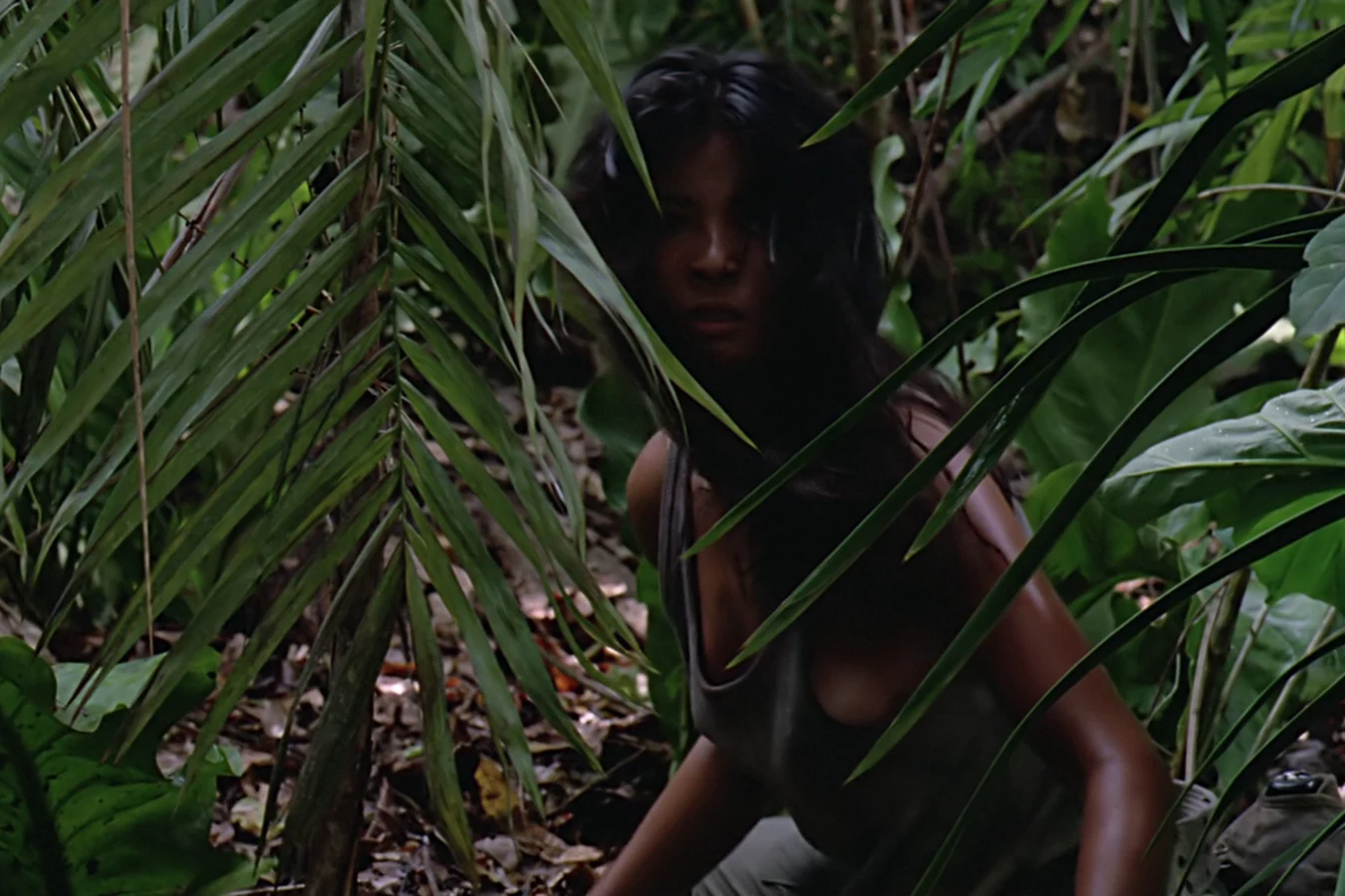 Anna Gonsalves crouching among jungle ferns as she flees toward the river