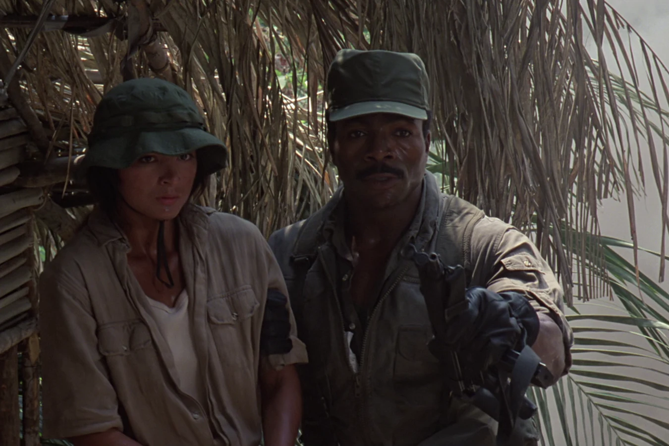 Anna Gonsalves in a bush hat standing beside Dillon at the destroyed guerrilla camp