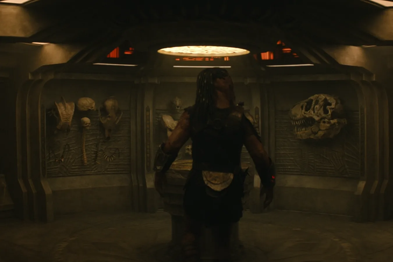 Dek standing before the complete trophy wall in Predator: Badlands