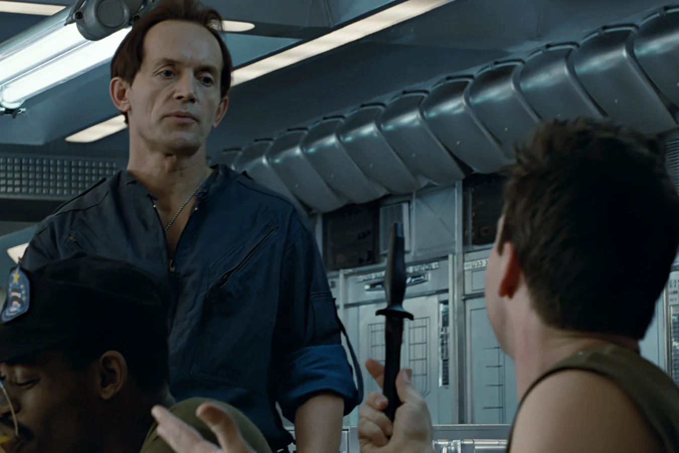 Bishop watching Hudson hold a combat knife in the Sulaco mess hall in Aliens