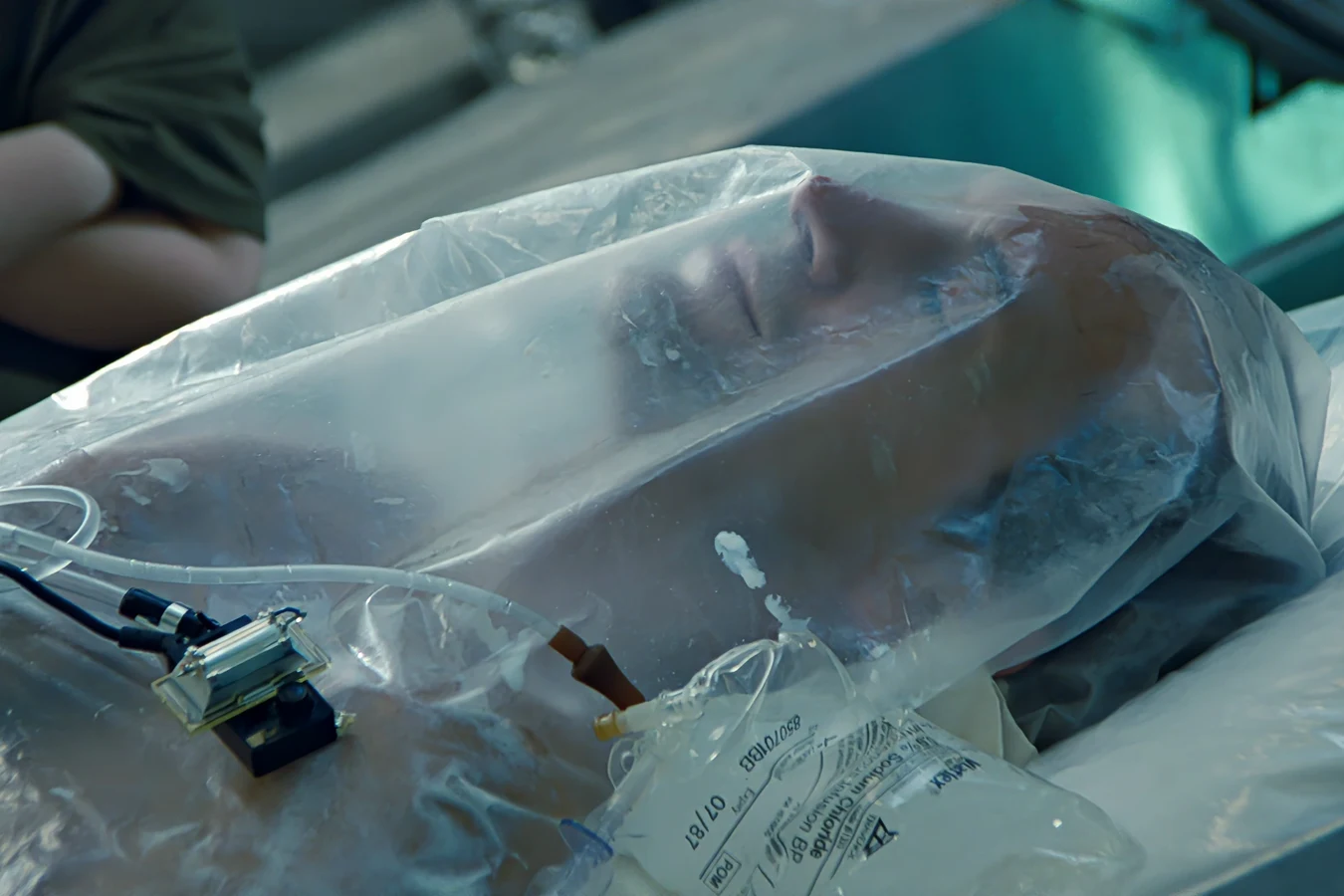 Bishop lying under a plastic sheet with medical tubing after his first activation