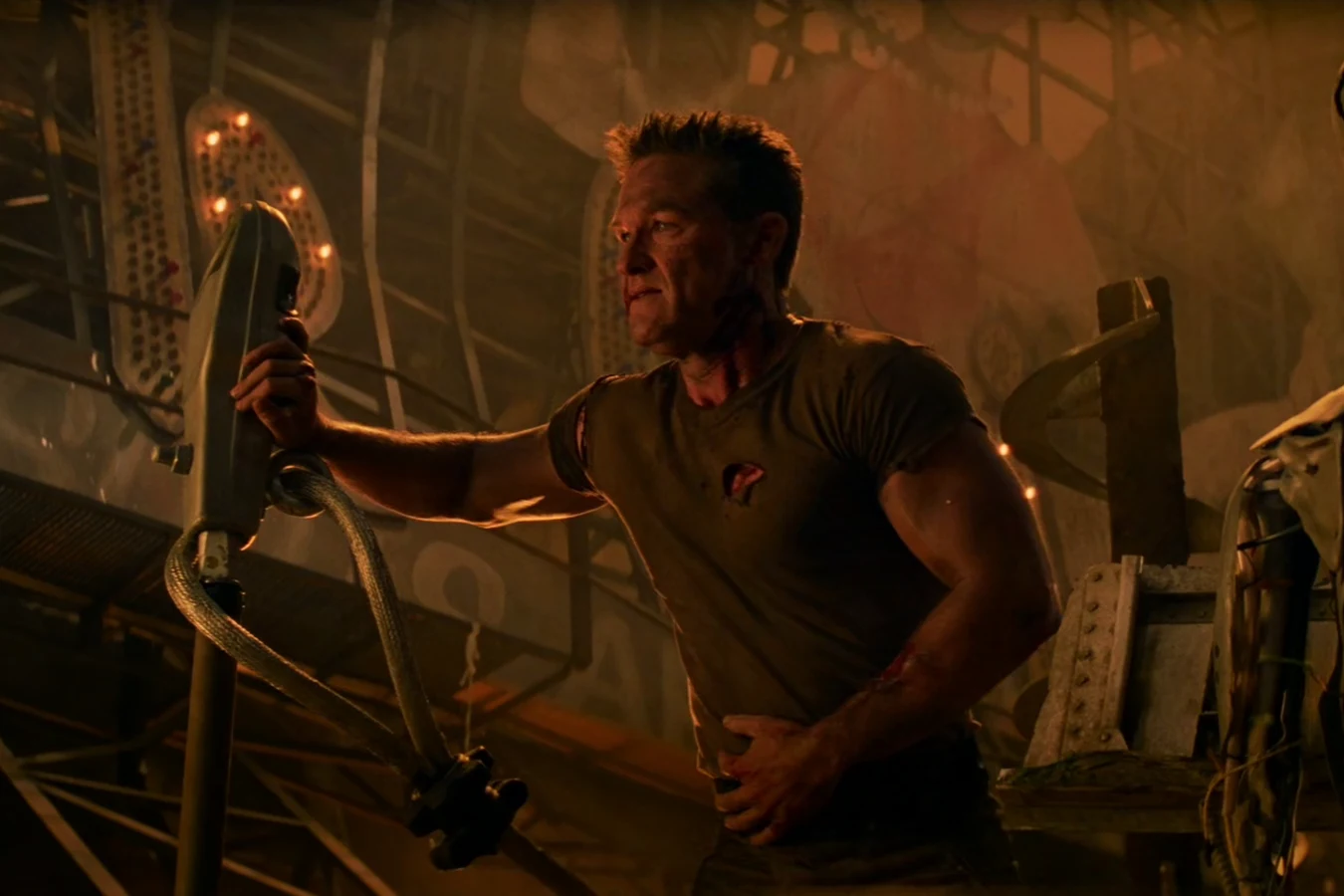 Kurt Russell as Todd gripping a cabled handset in an amber-lit, rusted hangar in Soldier