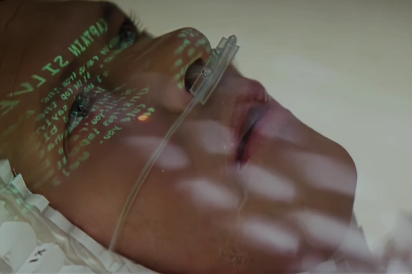 Dave Holden lying in a hospital bed with green text projected across his face in a deleted Blade Runner scene
