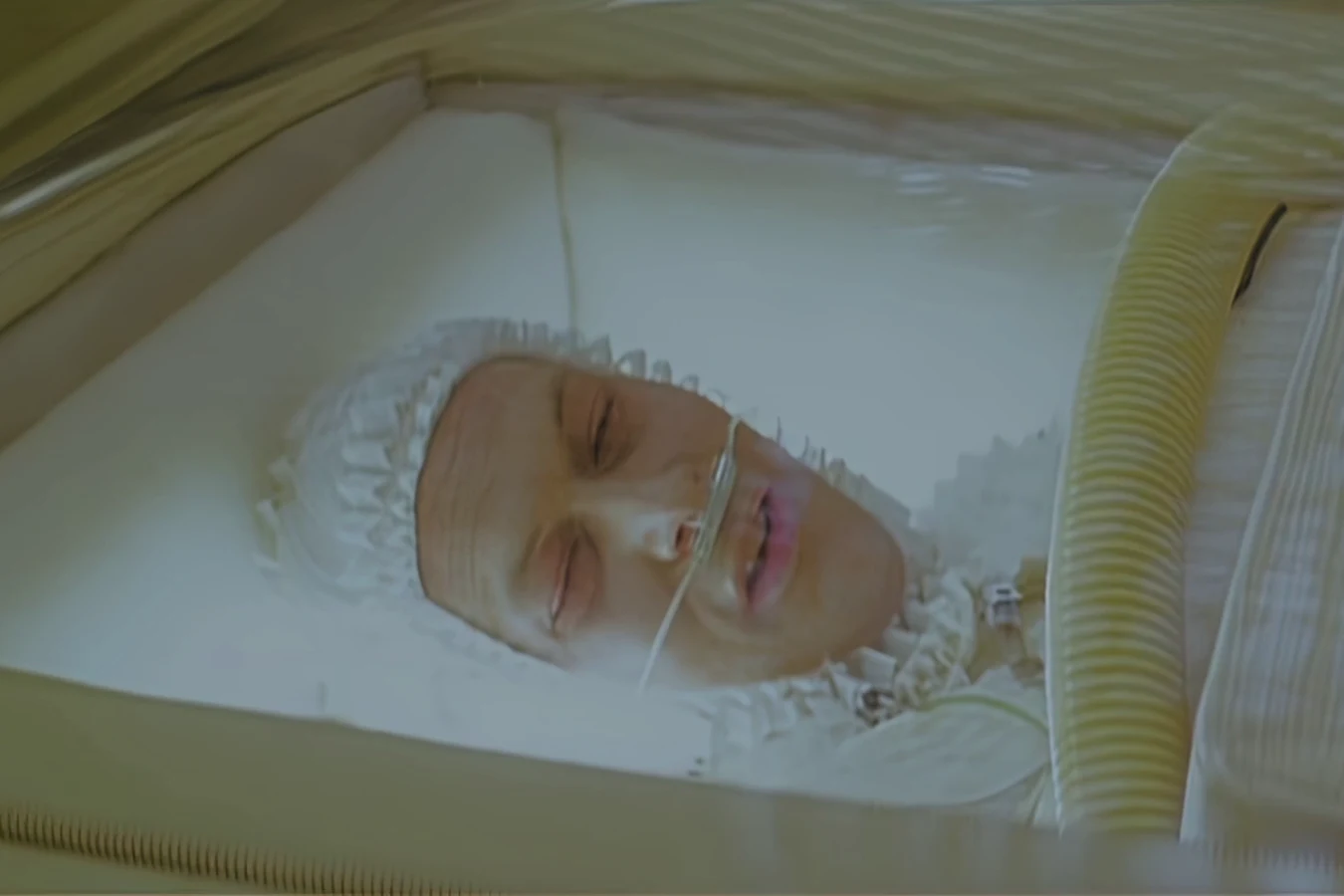 Dave Holden asleep in a ruffled cap inside a clear life support capsule, with an oxygen tube under his nose, in a deleted Blade Runner scene