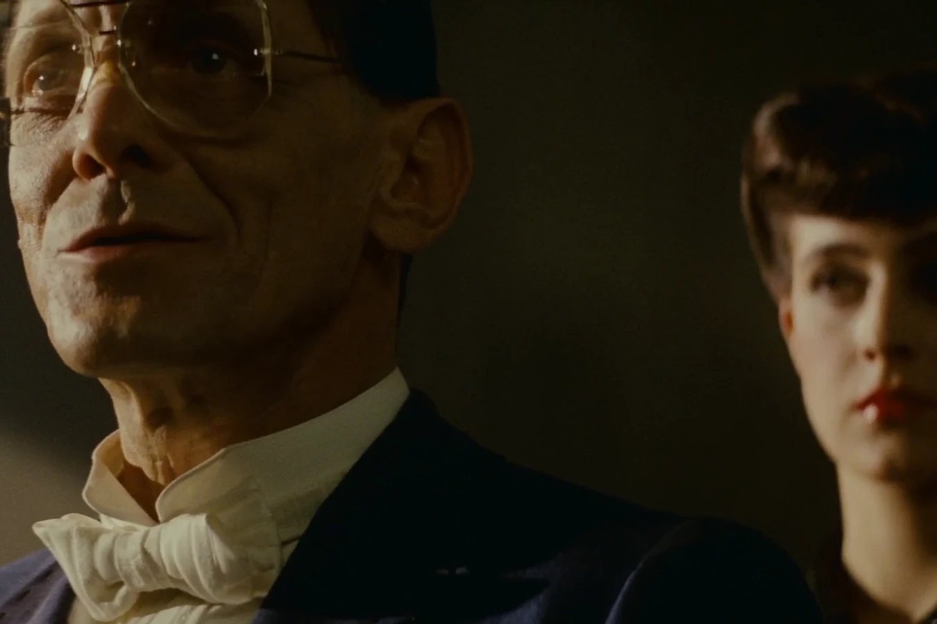 Eldon Tyrell in close-up with Rachael standing behind him in his office in Blade Runner (1982)