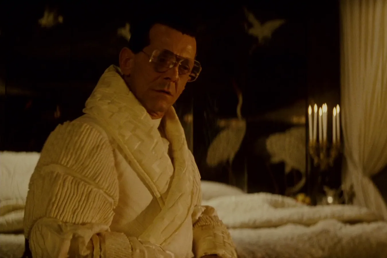 Joe Turkel as Eldon Tyrell sitting up in his white quilted robe in his candlelit bedroom in Blade Runner