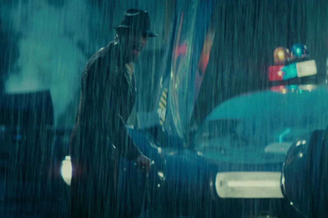 Edward James Olmos as Gaff beside a police spinner on the rainy rooftop after Roy Batty's death in Blade Runner