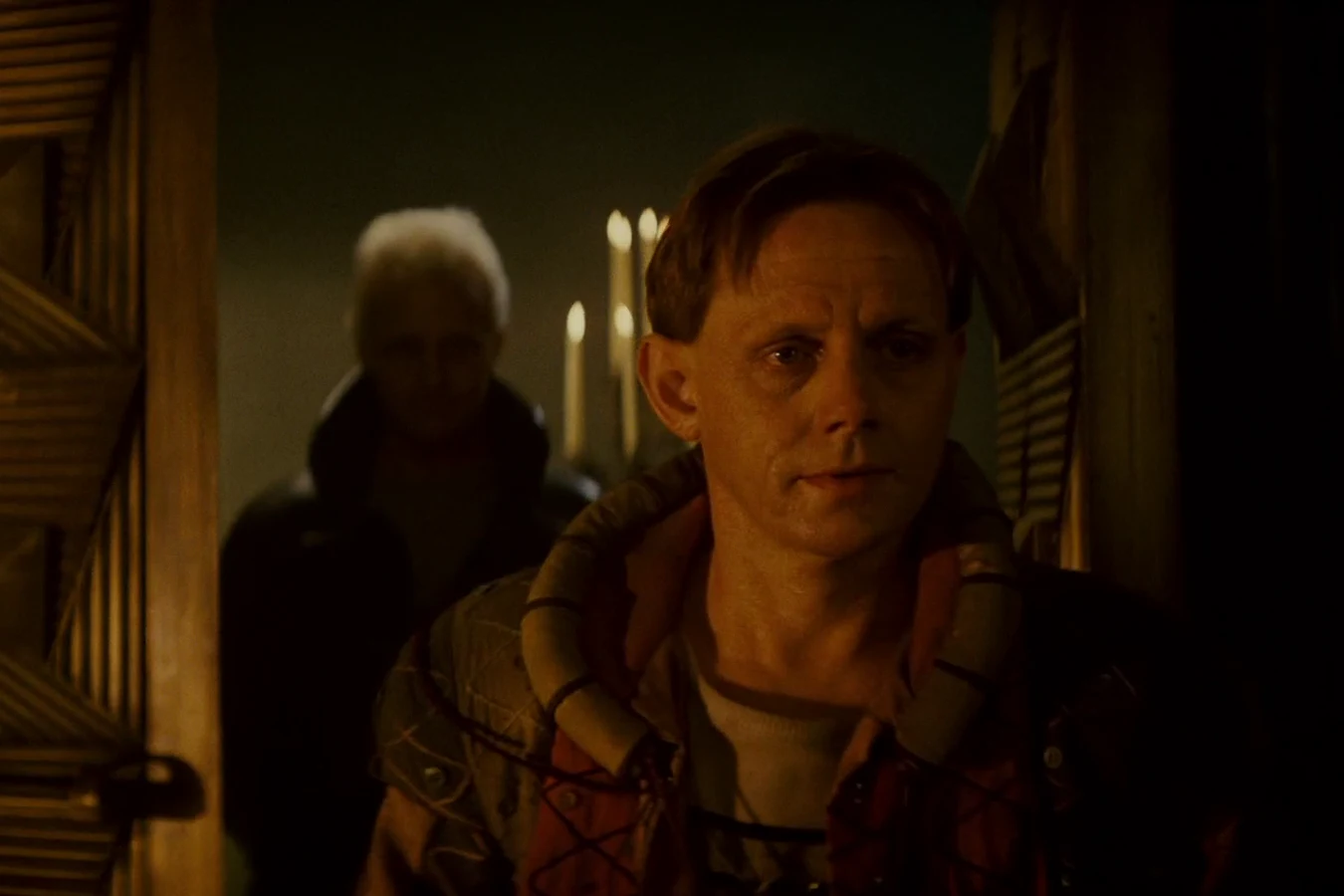 J.F. Sebastian entering Tyrell's candlelit bedroom with Roy Batty behind him in Blade Runner