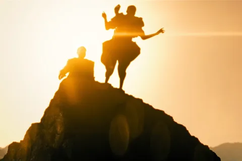 Silhouetted figures on a rocky peak against a golden sky, a Mercer-climb image from Blade Runner 2099 trailer material