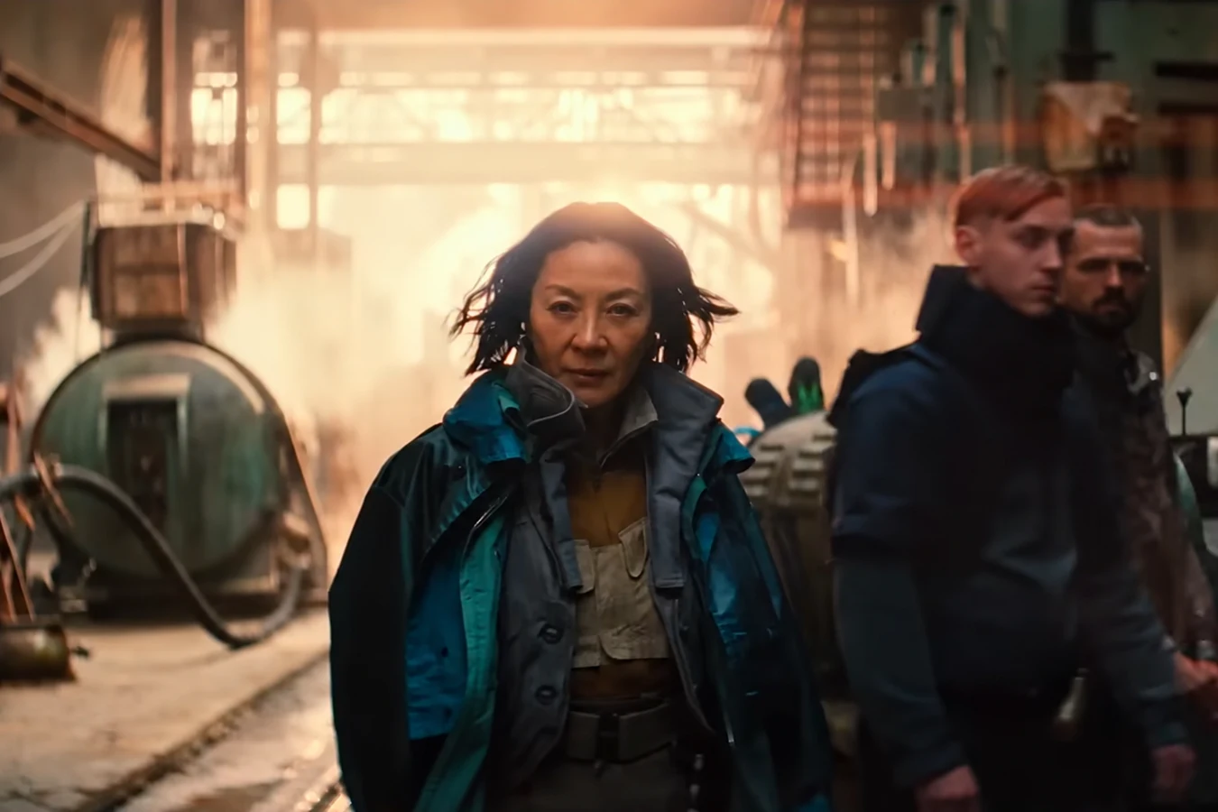 Michelle Yeoh as Olwen walking through an industrial interior in a teal jacket in Blade Runner 2099