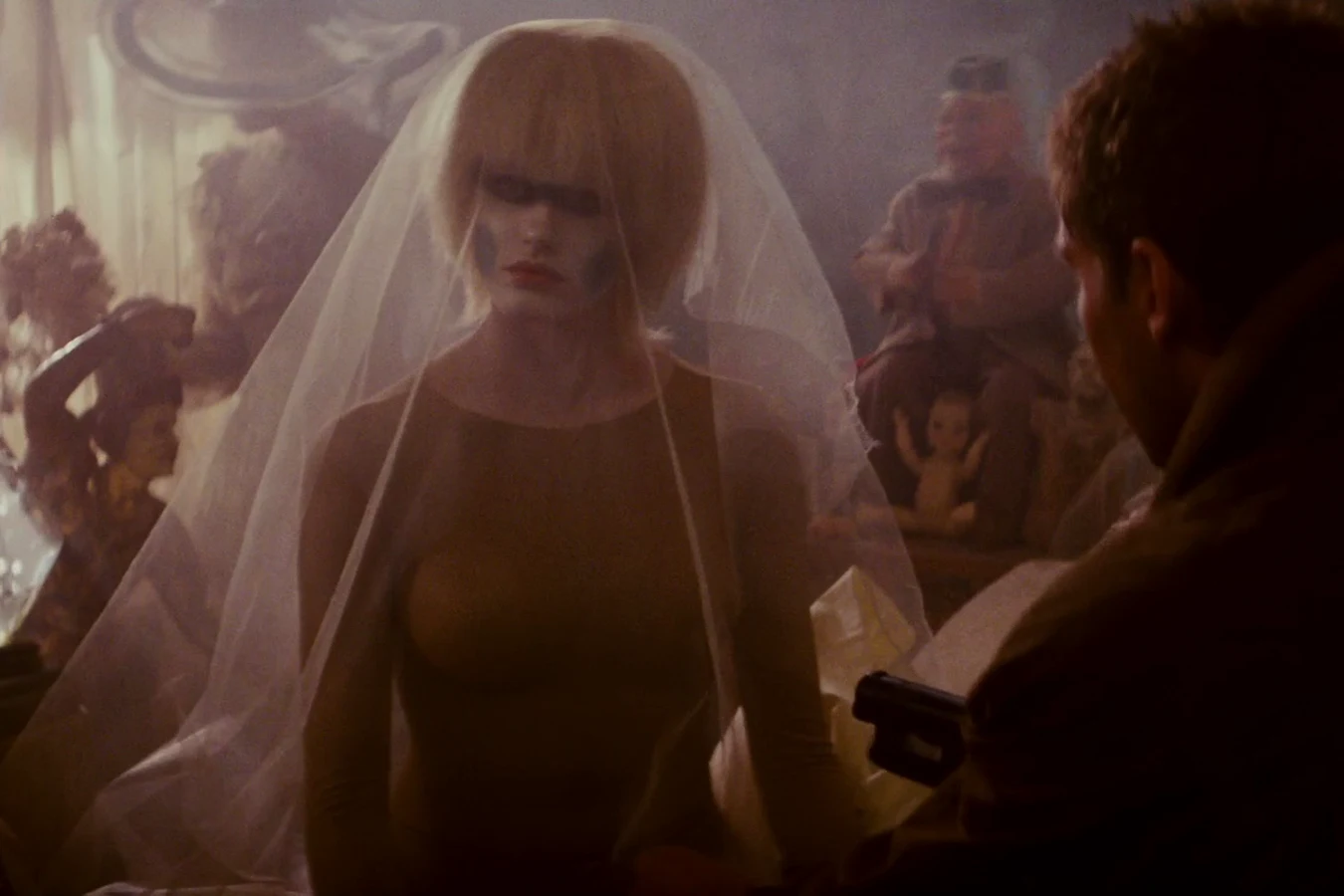 Pris disguised under a veil among Sebastian's toys as Deckard approaches with his gun in Blade Runner