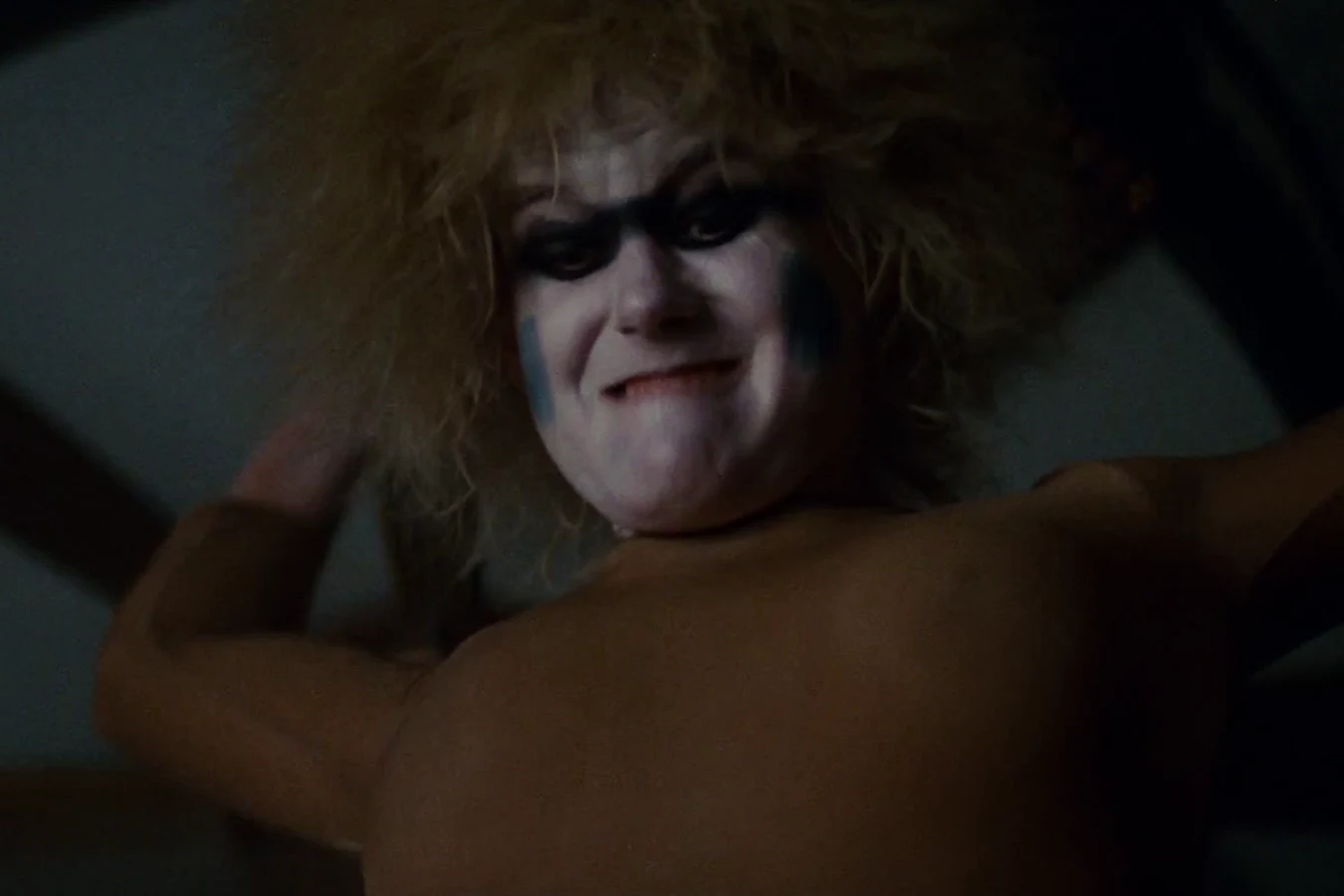Pris grinning down from on top of Deckard as she pins him during their fight in Blade Runner