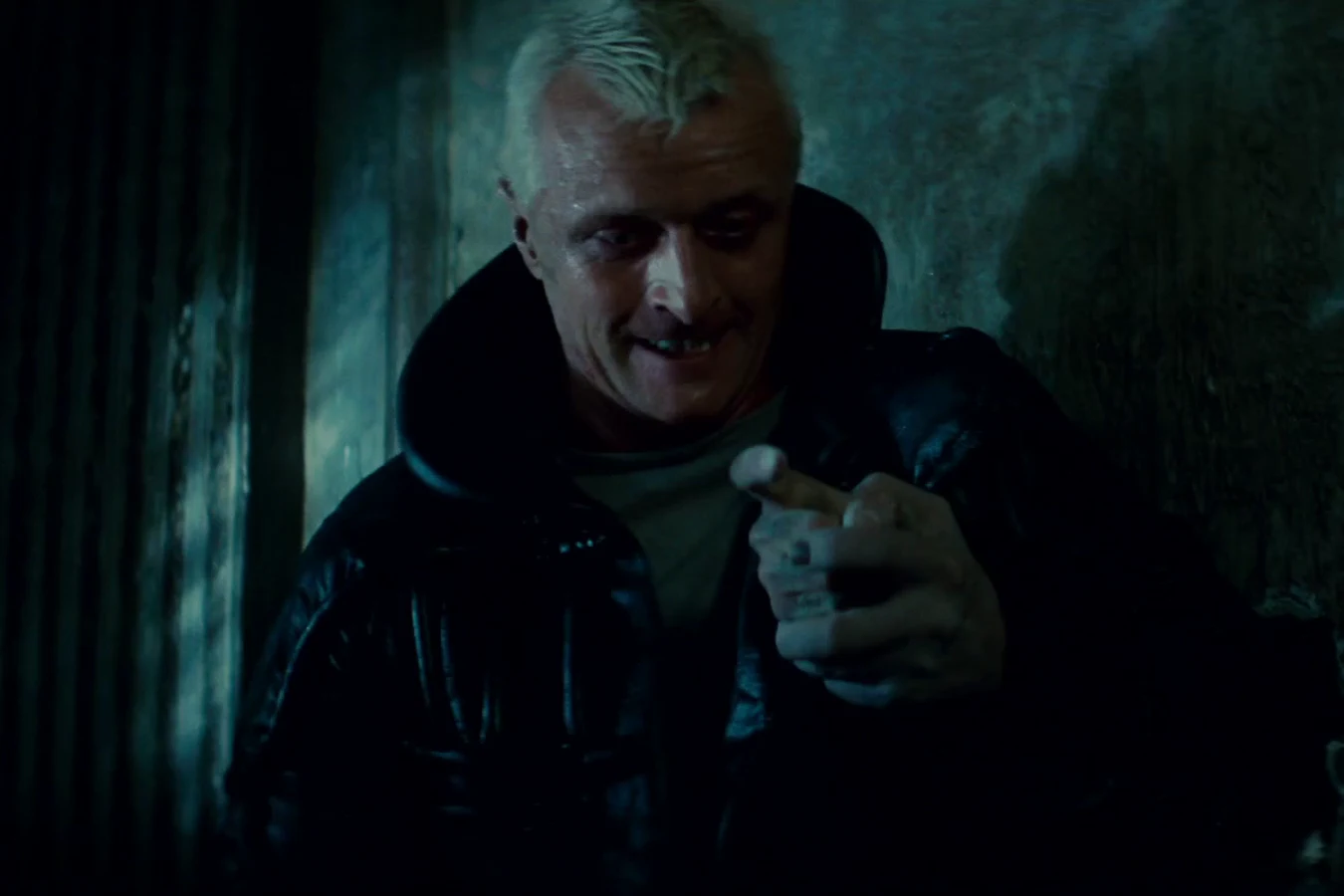 Rutger Hauer as Roy Batty grinning in a dark hallway of the Bradbury Building in Blade Runner