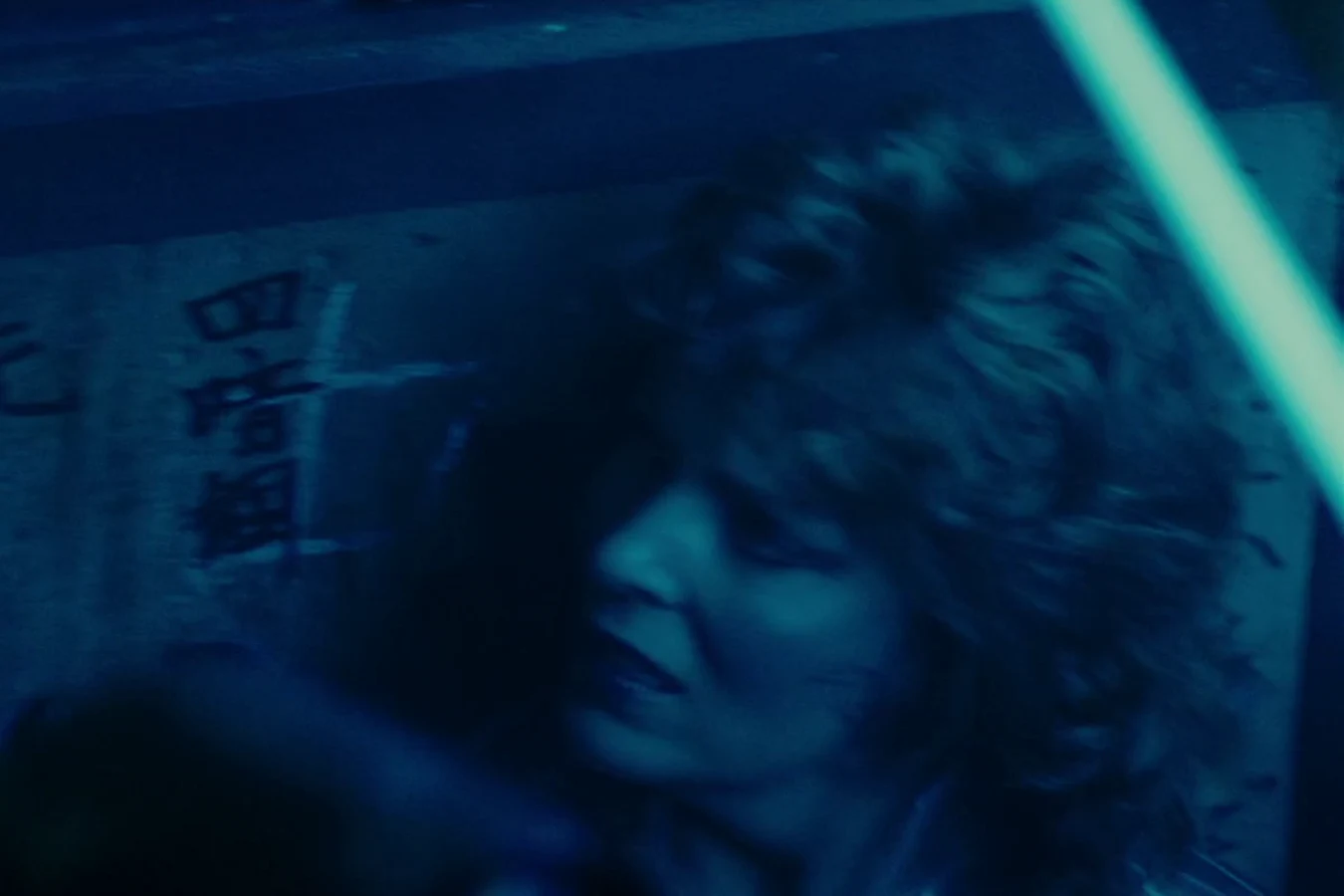 Zhora in her clear raincoat running across a car in the rainy neon street in Blade Runner