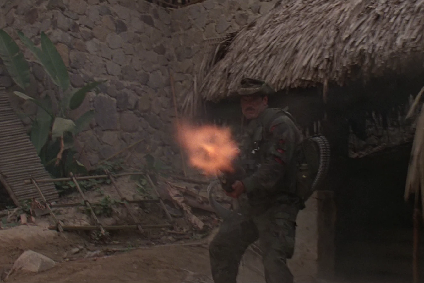 Blain Cooper firing his minigun among the huts of the guerrilla camp in Predator