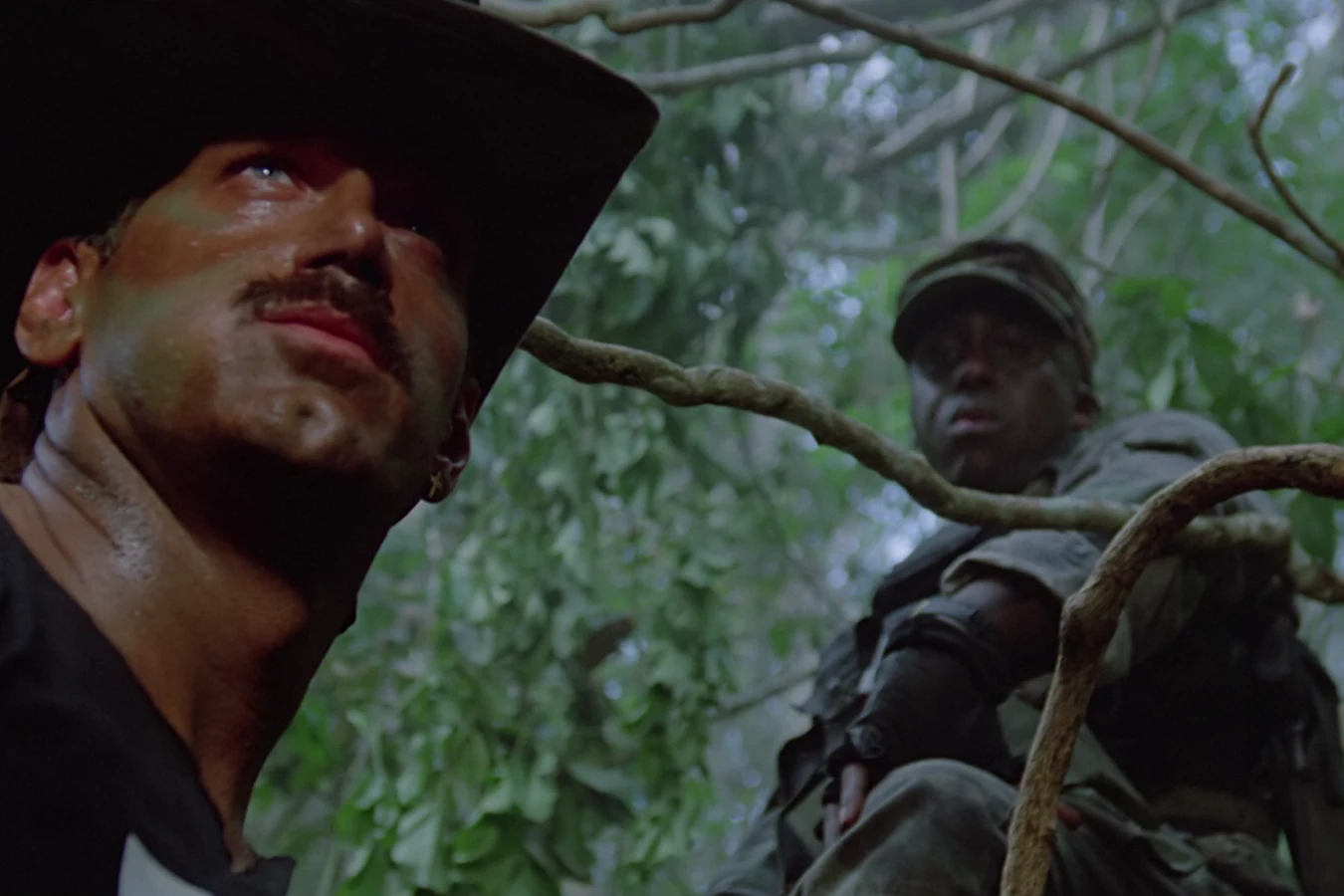 Blain Cooper scanning the jungle canopy with Mac behind him in Predator
