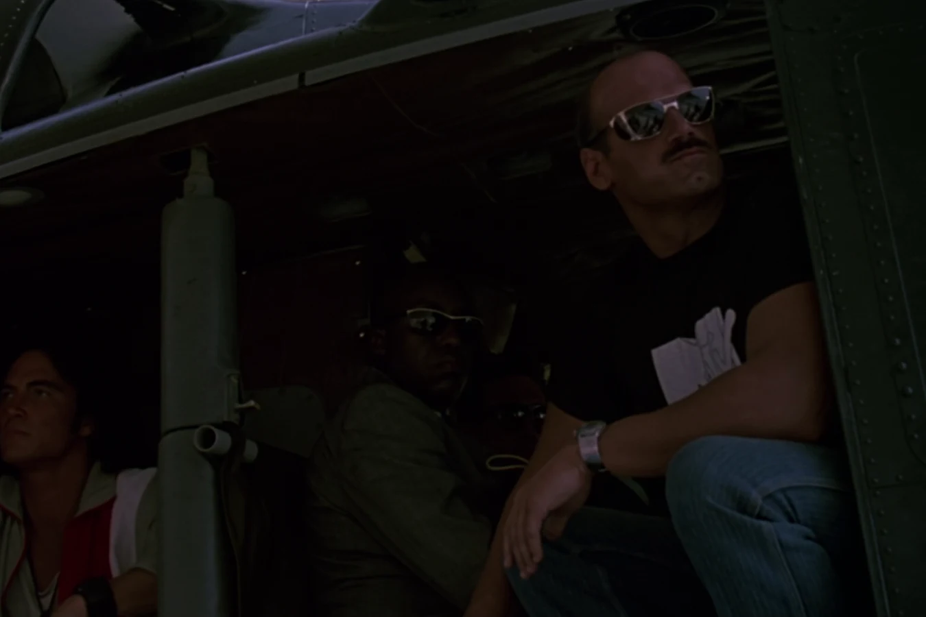 Blain Cooper in sunglasses and a black T-shirt aboard the helicopter that brought Dutch's team to the base in Predator
