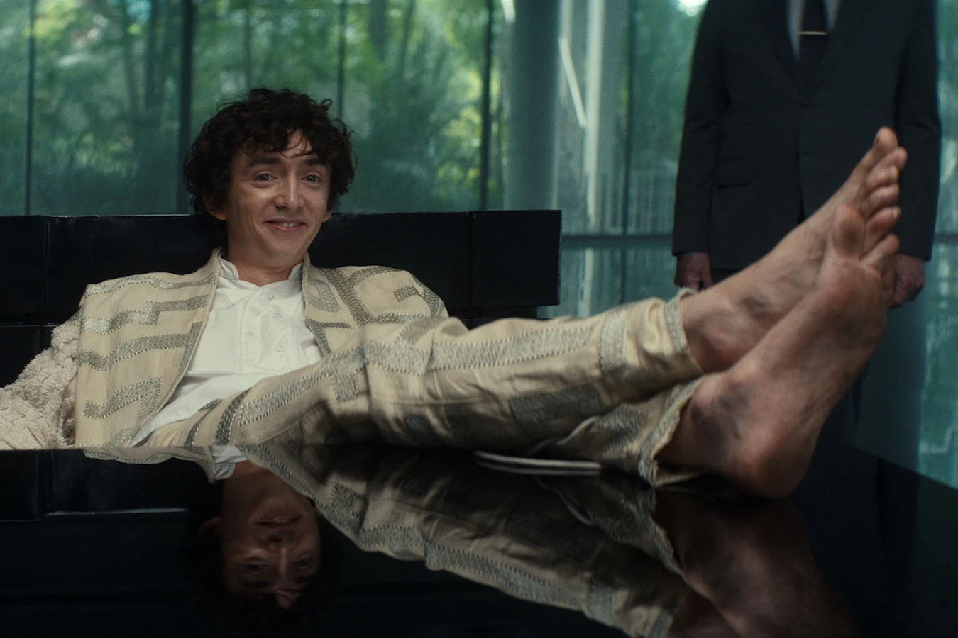 Boy Kavalier leaning back with his bare feet on the table during the arbitration hearing in Alien: Earth