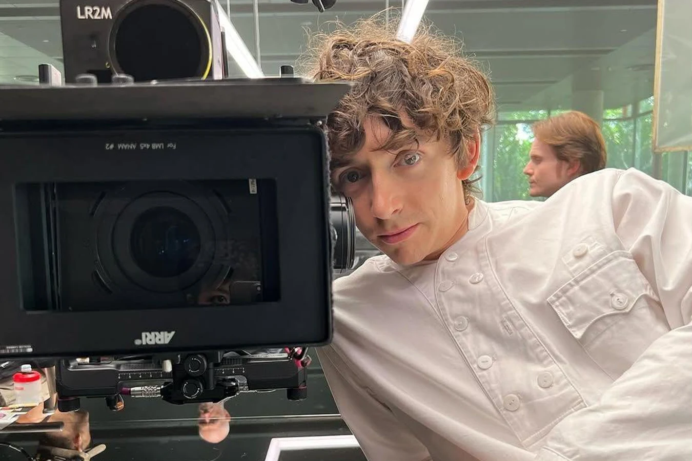 Samuel Blenkin in costume as Boy Kavalier leaning beside an ARRI camera on the set of Alien: Earth