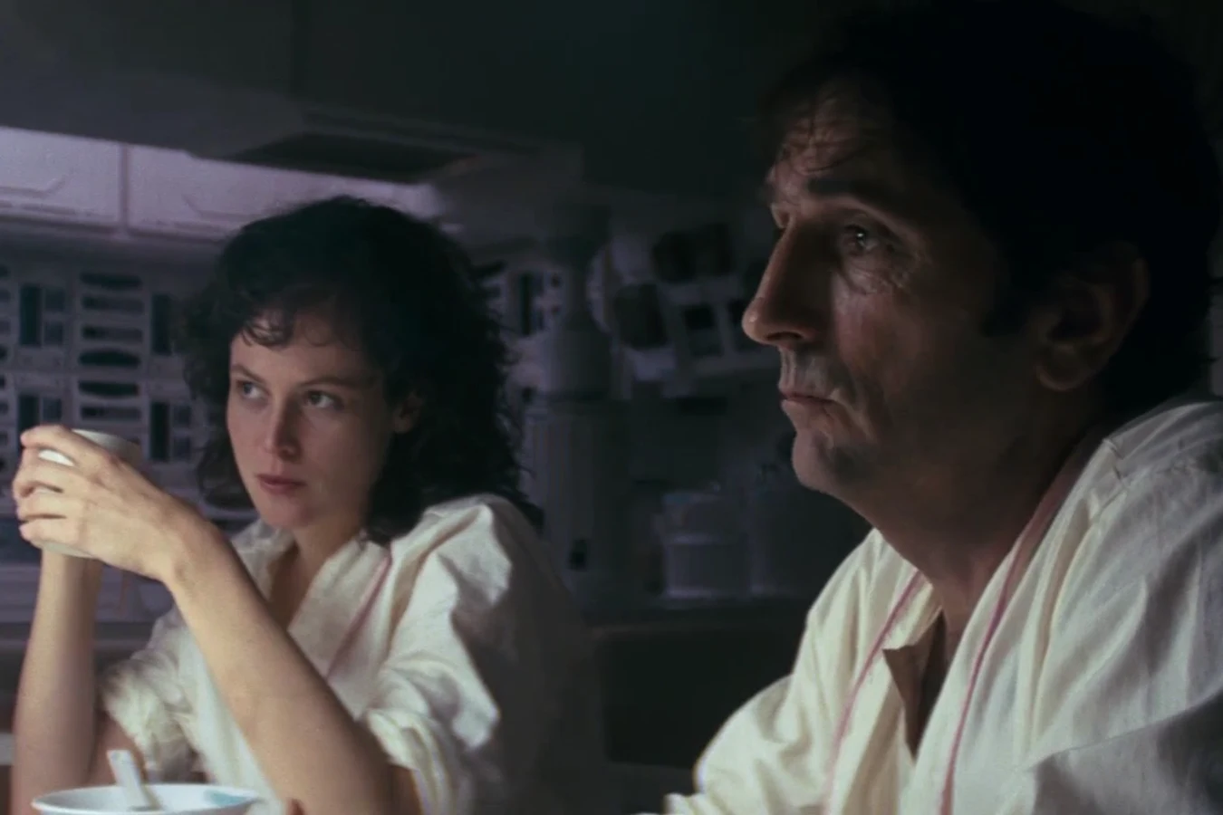 Brett in the foreground of the Nostromo mess, with Ripley holding a cup, in Alien