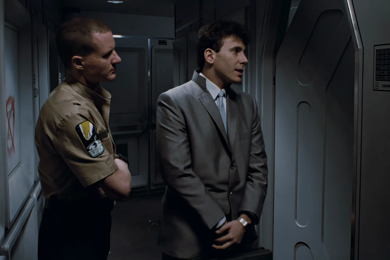 Carter Burke and Lieutenant Gorman at the door of Ellen Ripley's apartment on Gateway Station in Aliens