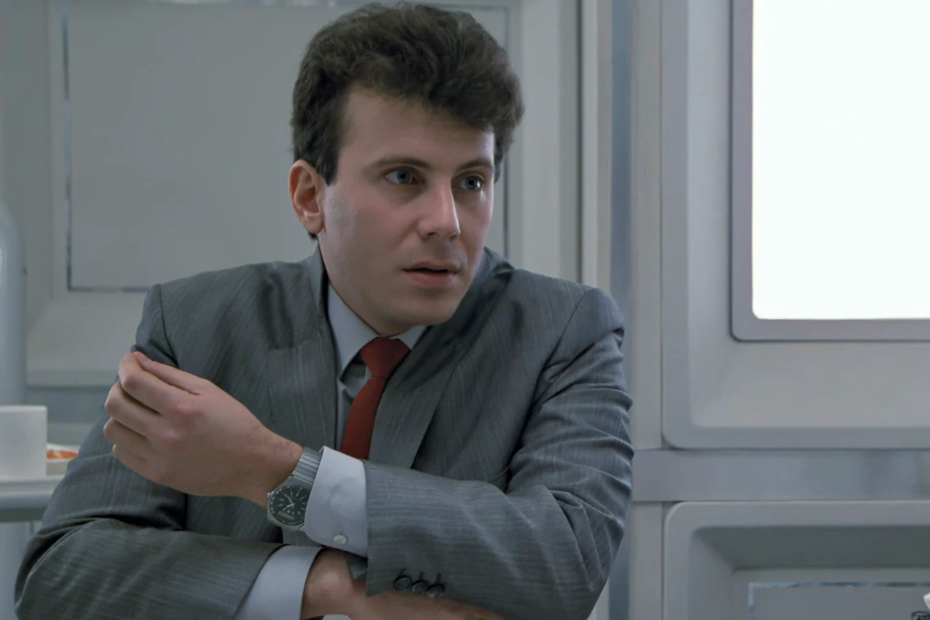 Carter Burke in a grey suit and red tie in Aliens