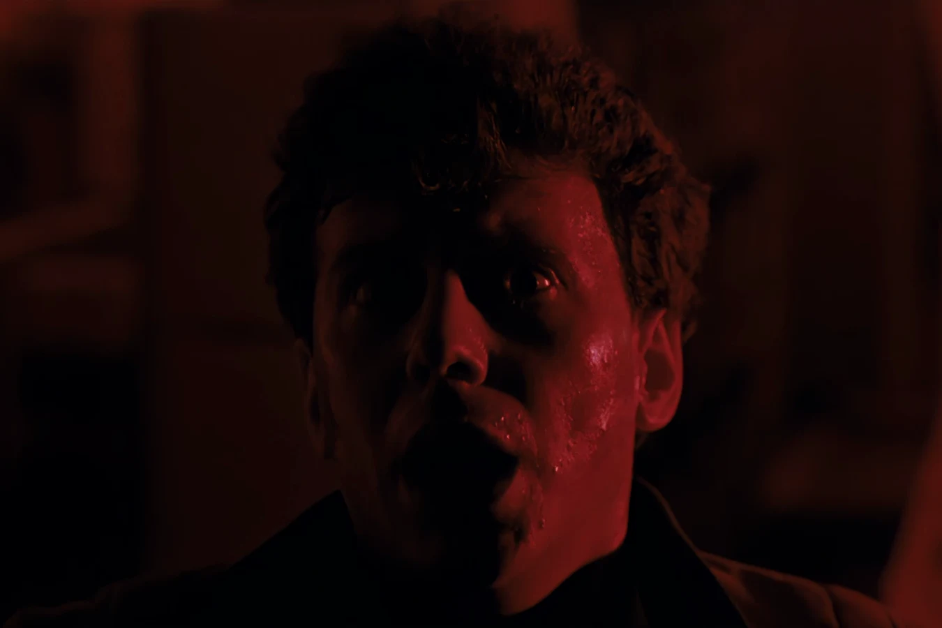 Carter Burke's face under red light as a Xenomorph takes him in Aliens