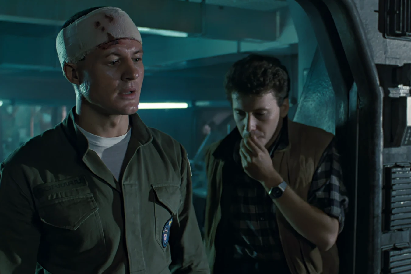 Carter Burke with his hand to his mouth beside a bandaged Lieutenant Gorman in Aliens