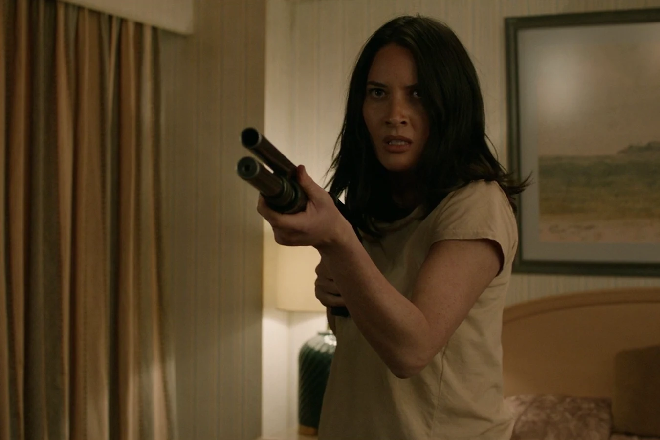 Casey Brackett aiming a gun in a motel room after waking up among the Loonies