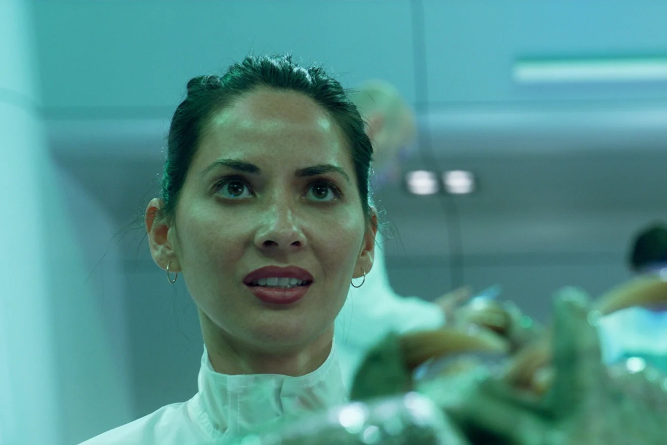 Casey Brackett in white lab scrubs beside the sedated Fugitive Predator, with a blond scientist watching