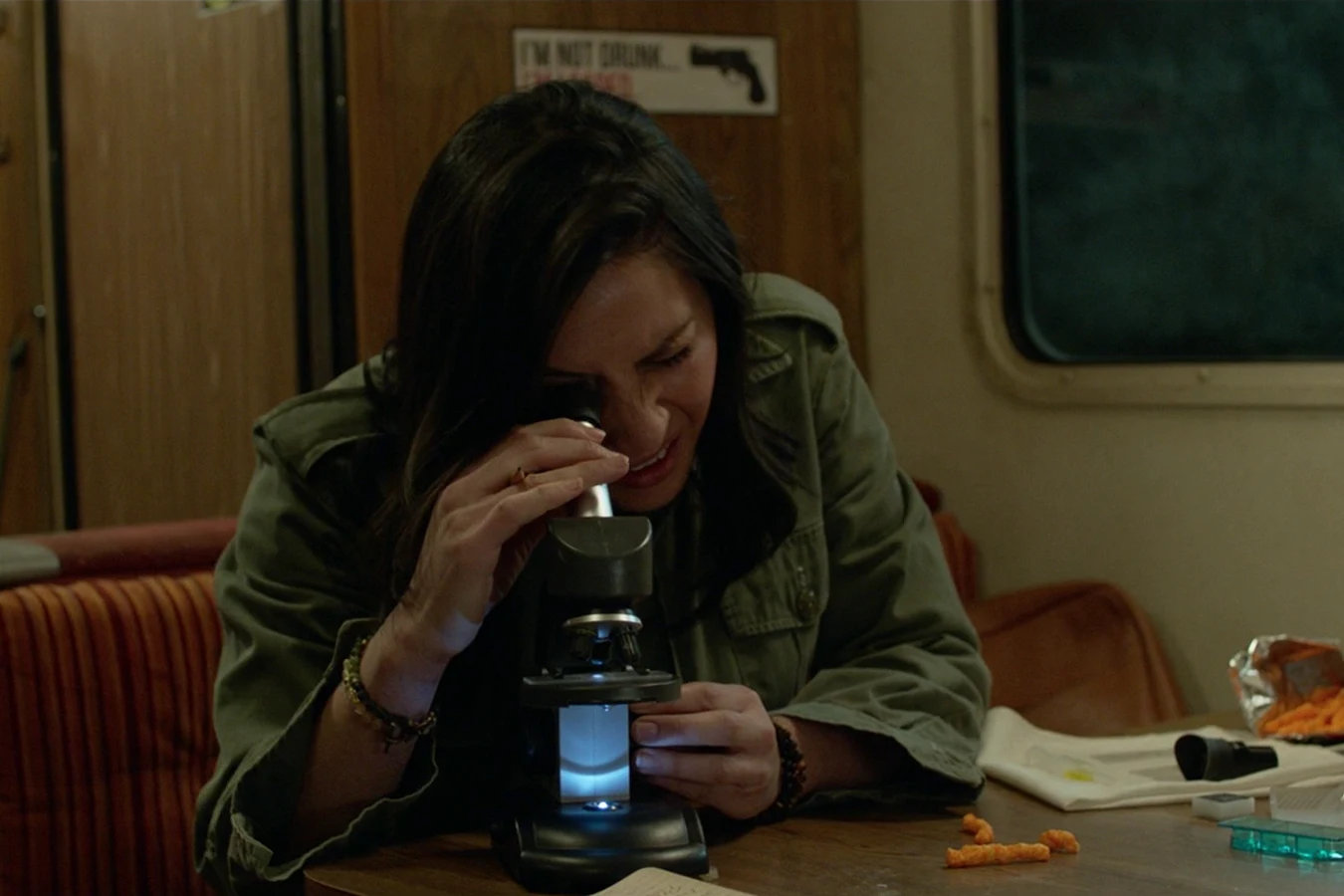 Casey Brackett looking through a portable microscope at the table inside the Loonies' motor home
