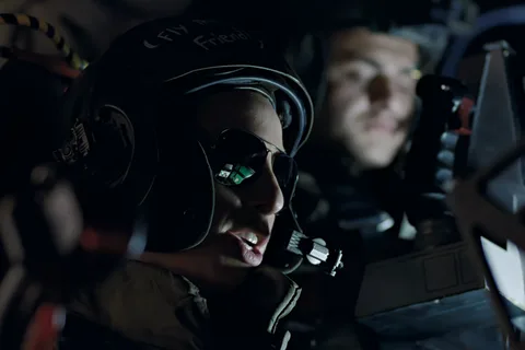 Corporal Colette Ferro in a flight helmet and sunglasses at the Bug Stomper controls in Aliens, with Spunkmeyer behind her