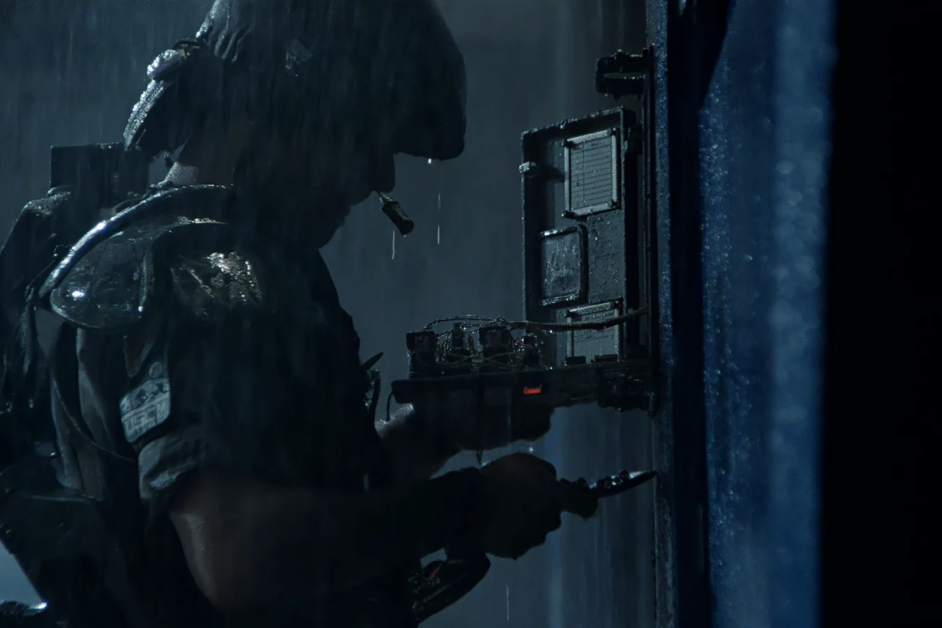 Colonial Marine using a ComTech Hacking Device on a wall access panel in the rain
