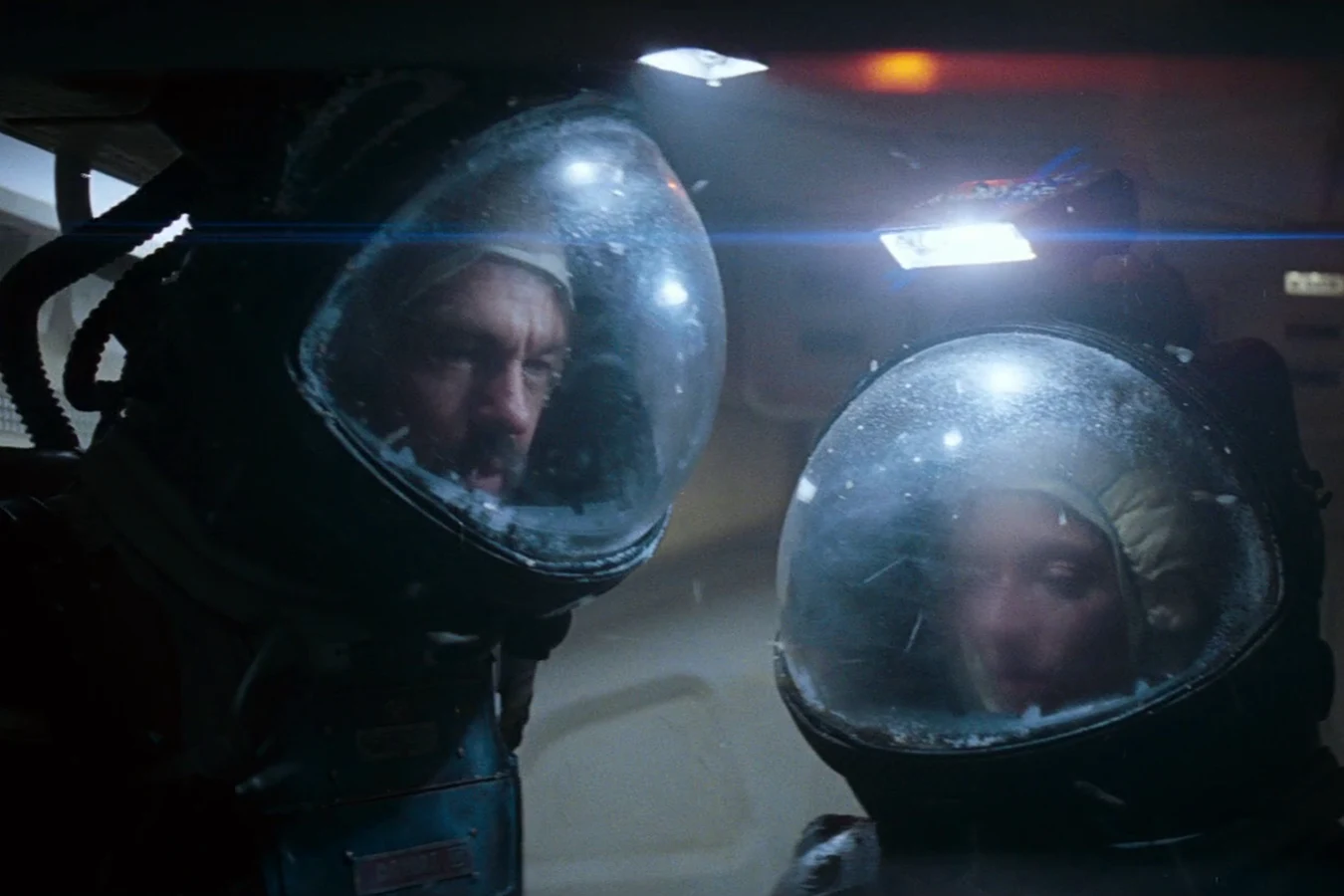 Dallas and Lambert in helmets looking down at Kane after the Facehugger attack in Alien