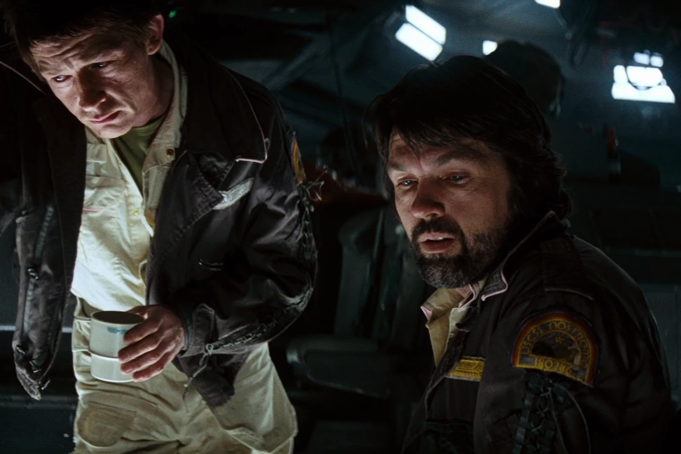 Dallas at a Nostromo console with Kane standing beside him holding a cup