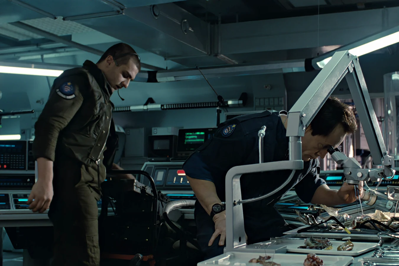 Daniel Spunkmeyer in a flight suit and headset standing by Bishop at the Sulaco medlab microscope in Aliens