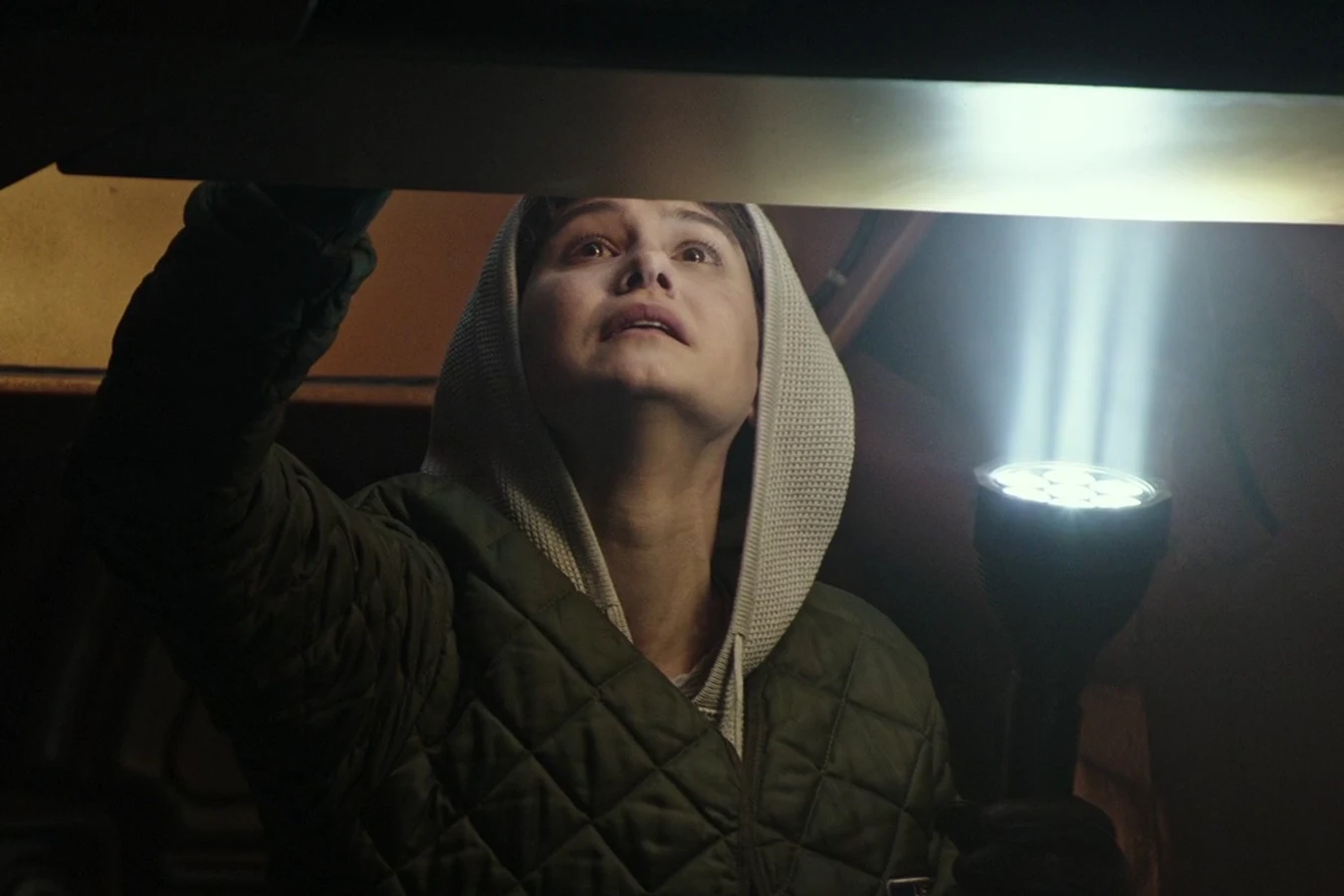 Daniels in a hooded jacket checking stores aboard the Covenant with a flashlight
