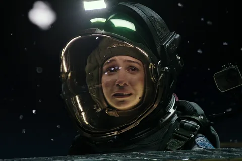 Daniels in an EVA helmet on the cargo lift outside the Covenant, debris floating past the visor