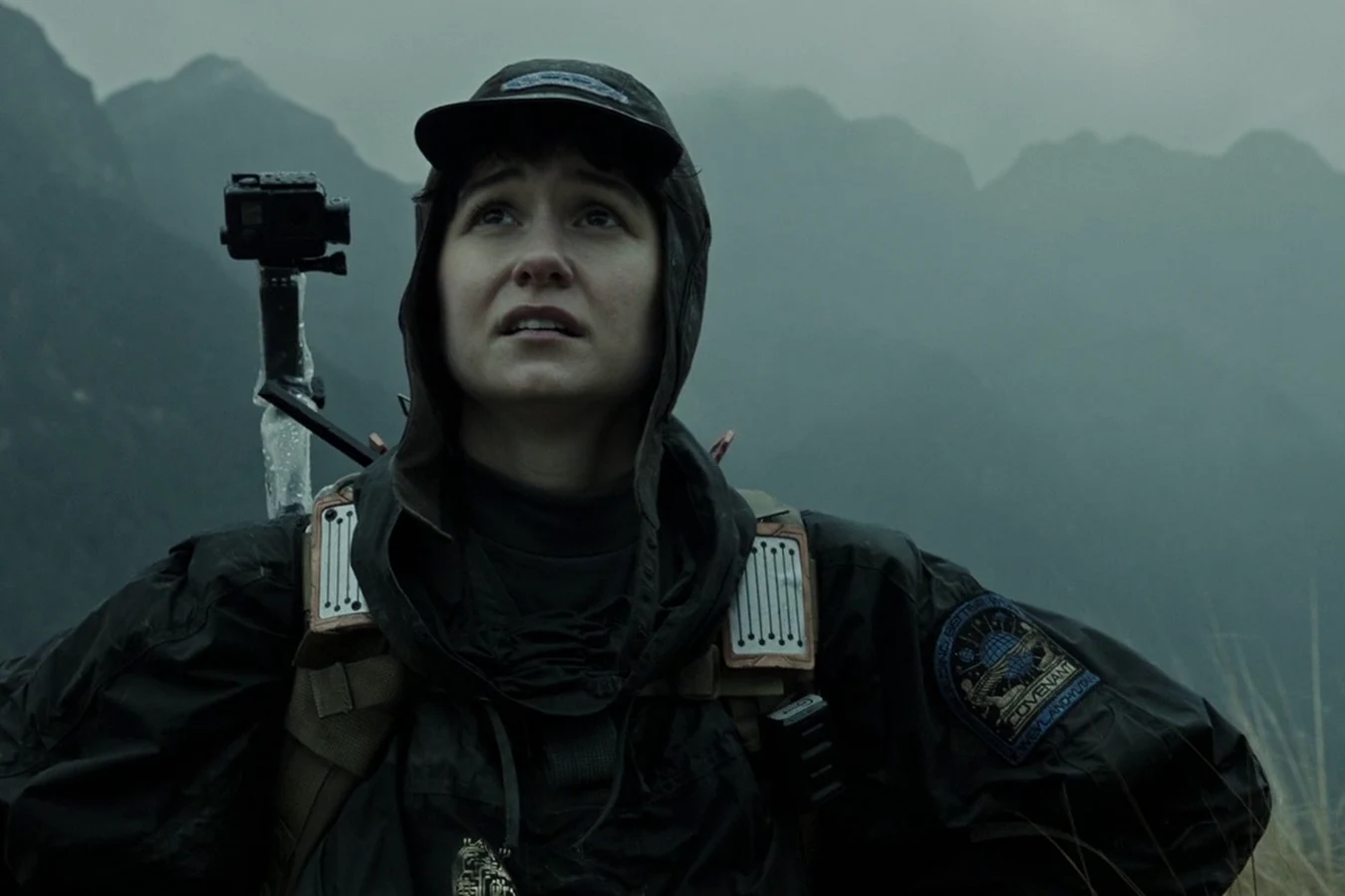 Daniels in rain gear on Planet 4, wheat and mountains behind her
