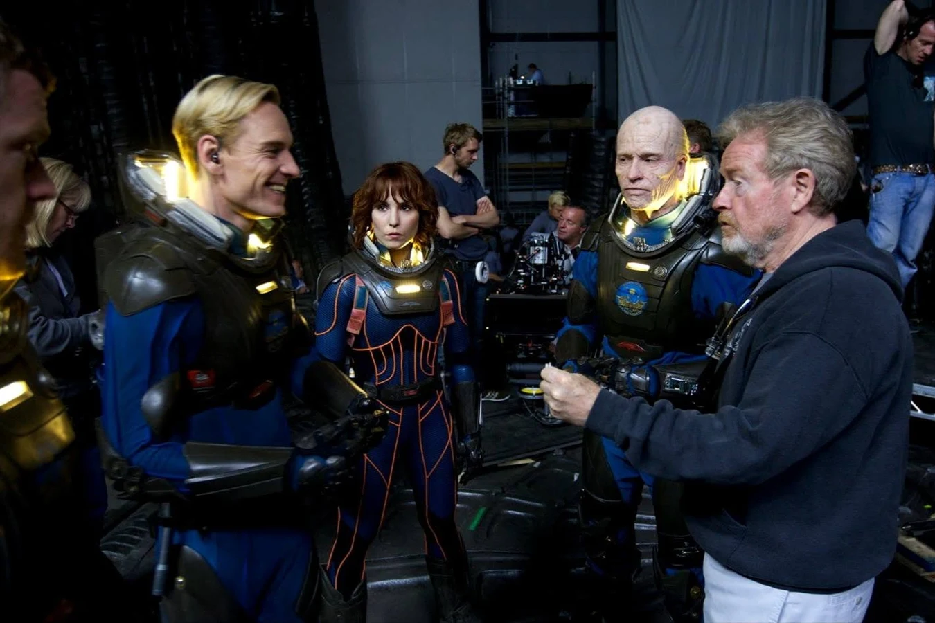 Michael Fassbender and Noomi Rapace in spacesuits beside Guy Pearce in old-age makeup and Ridley Scott on the Prometheus set