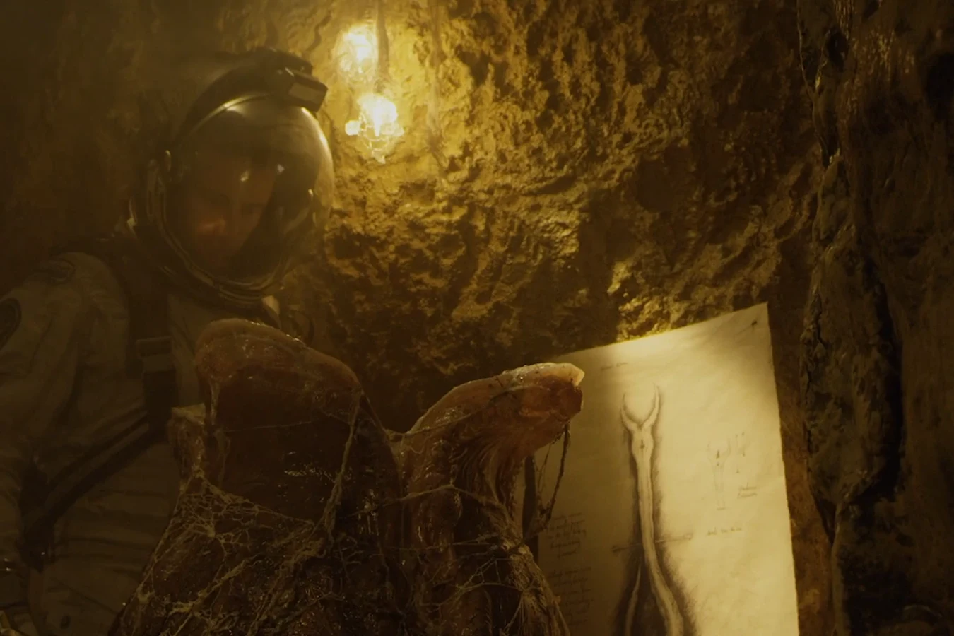 An explorer in a space helmet beside an opened egg and one of David's drawings in the laboratory on Planet 4