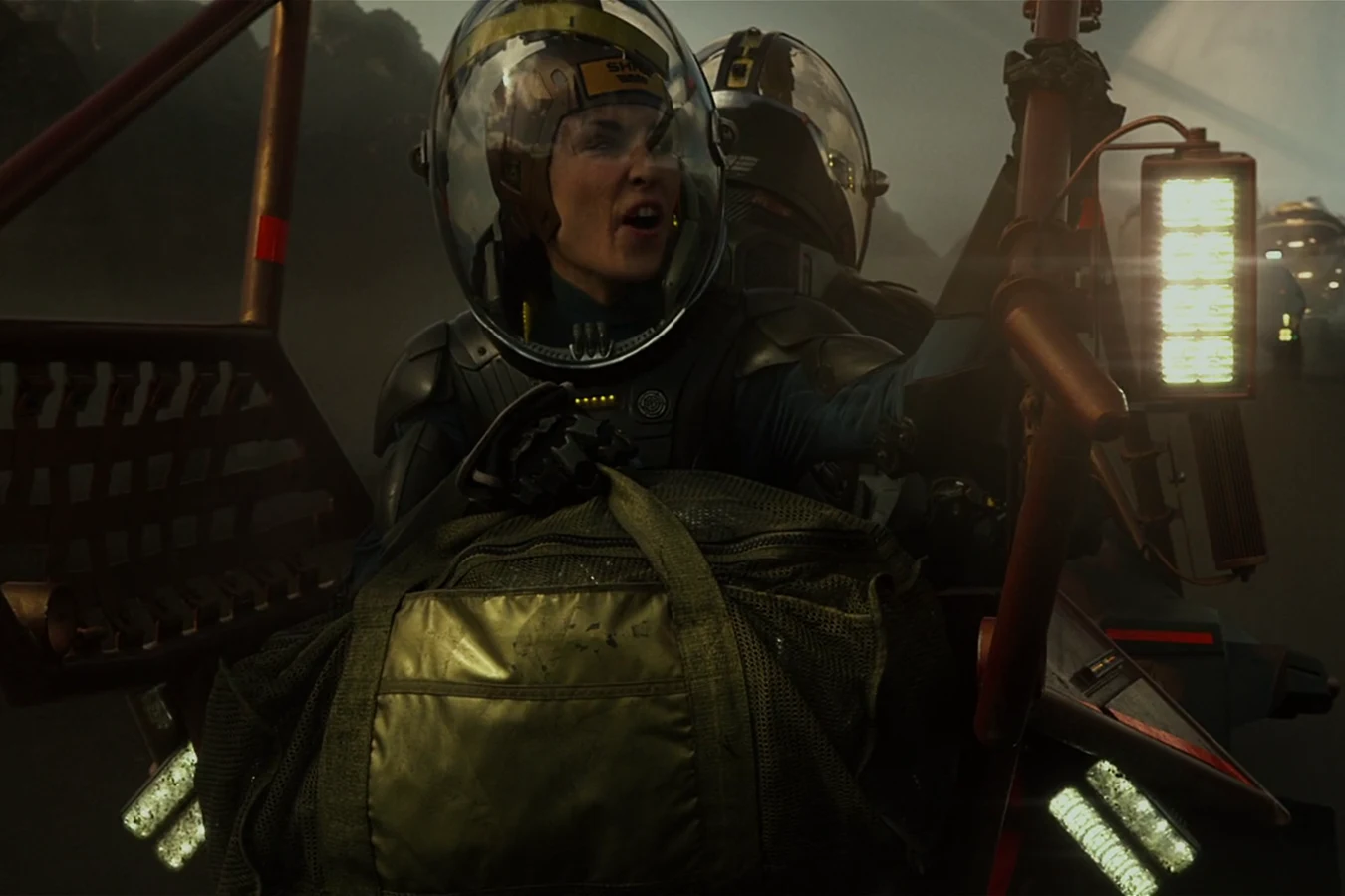 Elizabeth Shaw in her helmet on a rover during the silica storm on LV-223, a specimen bag in front of her