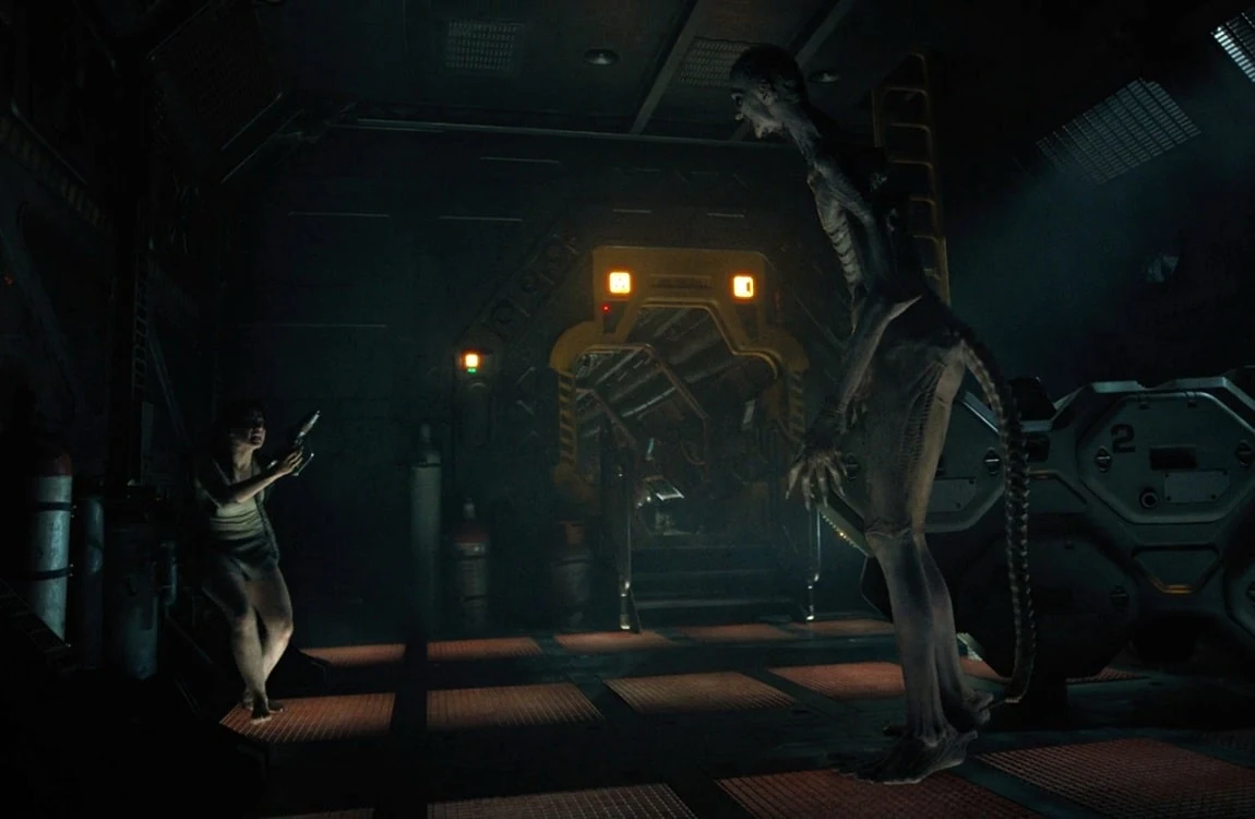 The Offspring from Alien: Romulus standing full-body in a corridor opposite Rain Carradine
