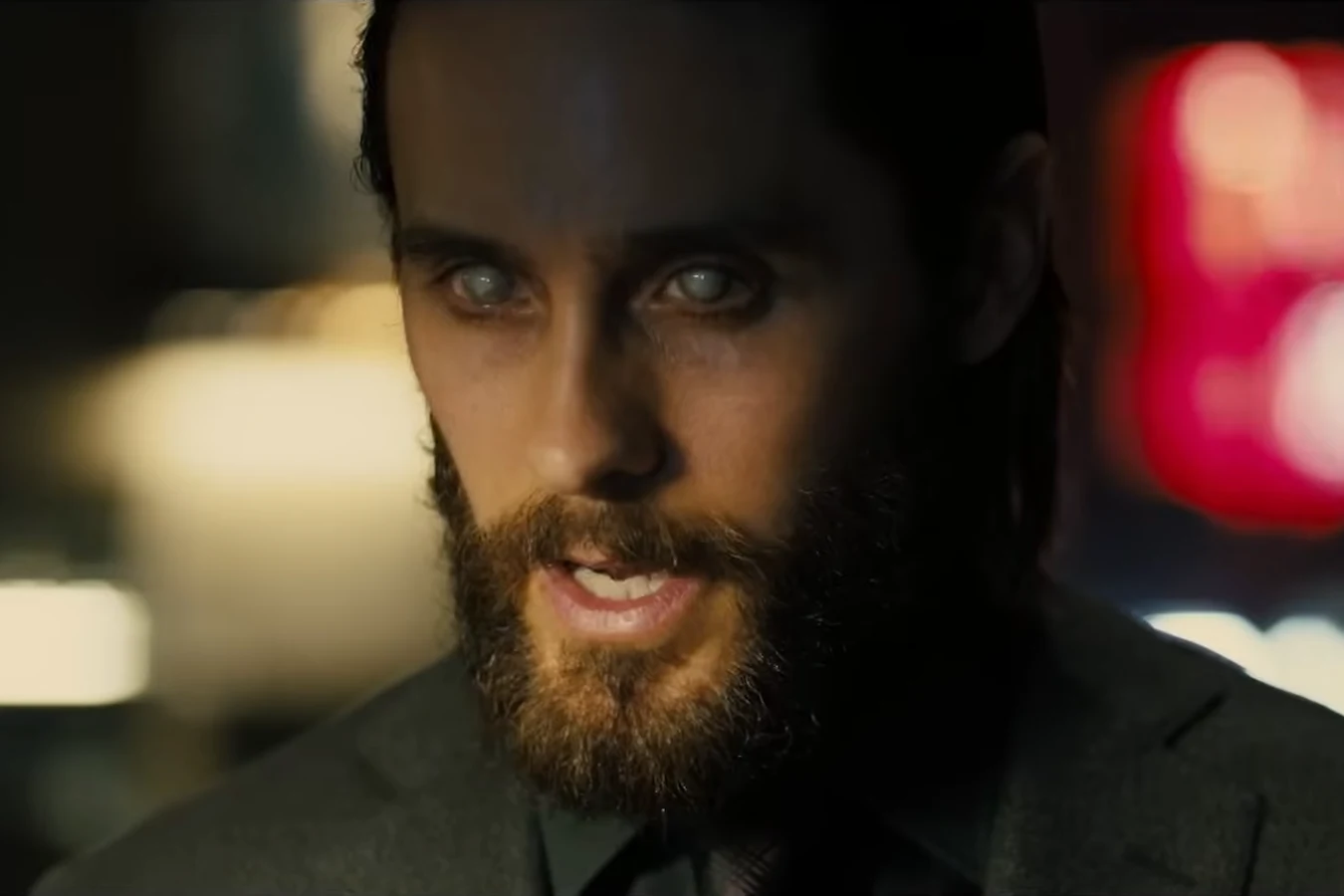 Niander Wallace speaking to the lawmakers in close-up with red and white lights behind him in 2036: Nexus Dawn