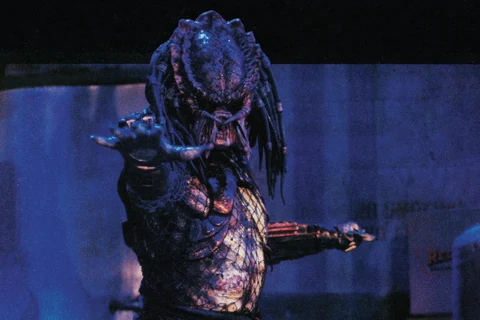 Photo cover of Dark Horse's Predator 2 #1, with the Predator reaching out a clawed hand in a dim, blue-lit warehouse