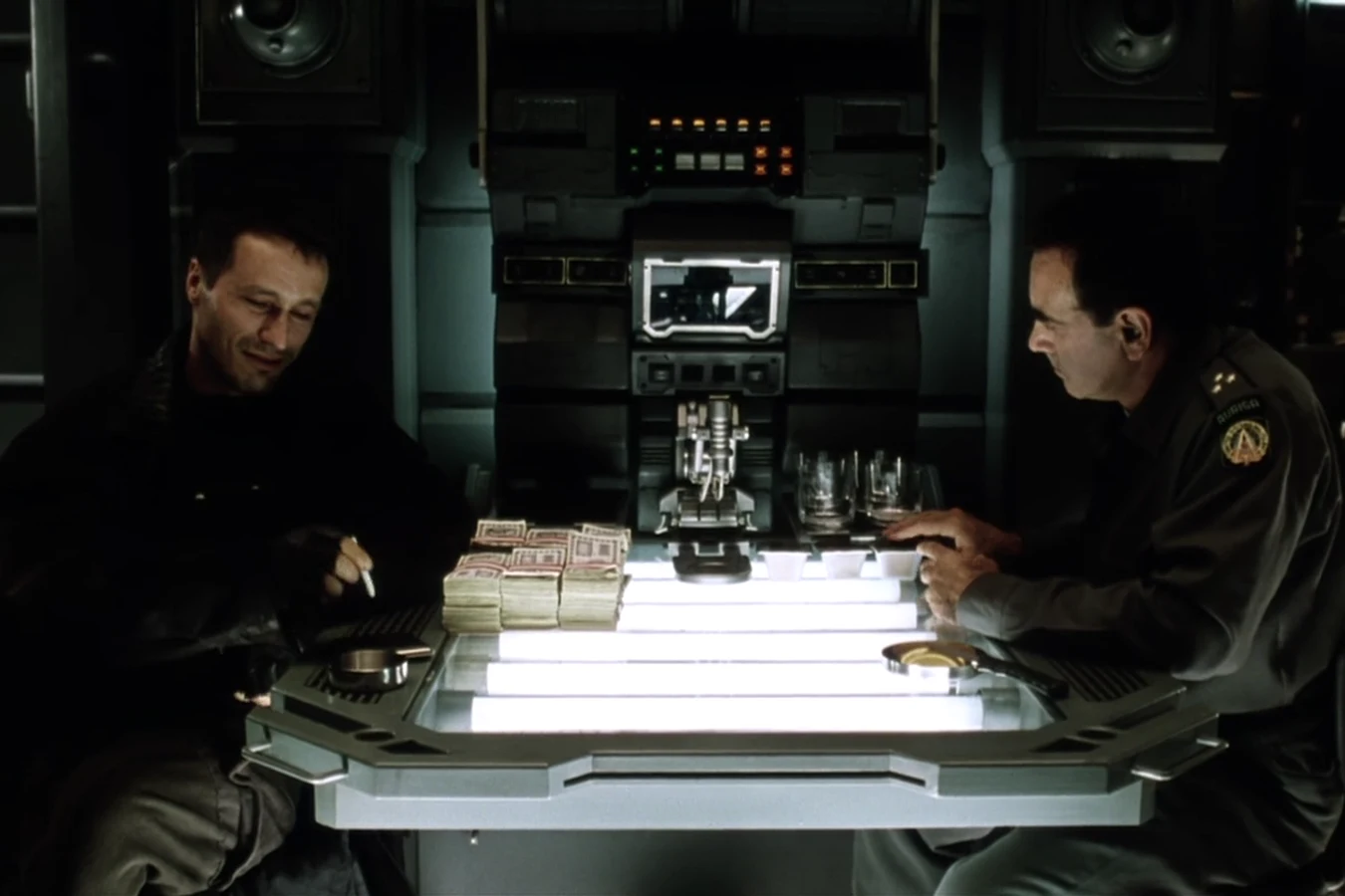Elgyn and Perez at a lit table stacked with cash aboard the Auriga