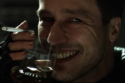 Elgyn grinning over a drink and a cigarette in Alien: Resurrection