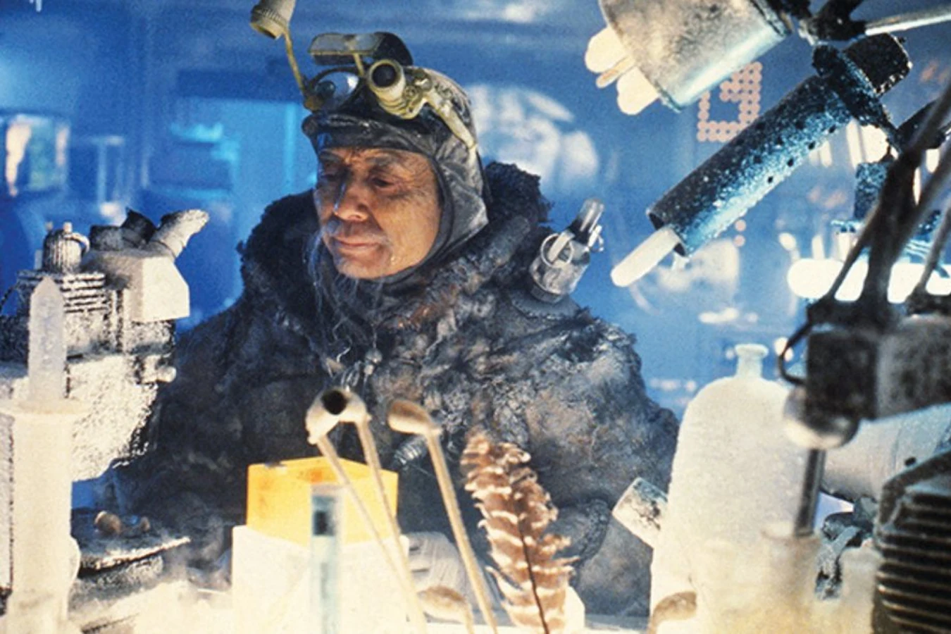 James Hong as Chew in a frosted fur coat and goggles at his workbench among iced lab equipment in a Blade Runner production still