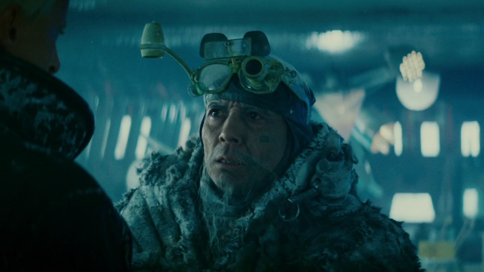 Chew in a frost-covered fur coat and magnifying goggles facing Roy Batty in his freezing eye lab in Blade Runner